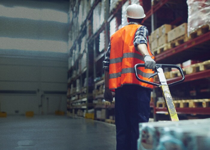 Person carrying packed boxes in warehouse.