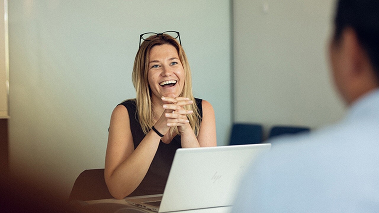 A female employee from the services and operations team smiling and conversing with a male employee.