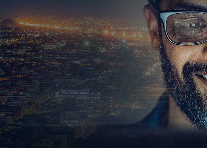 Technology careers at Maersk - A smiling employee with a city lit up at night in the background.