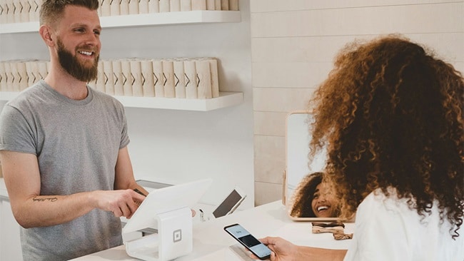 A man and woman stand together in front of a counter, engaged in conversation.