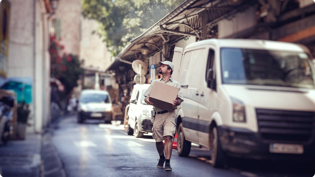 A man with a box under his arm, navigating a busy street.