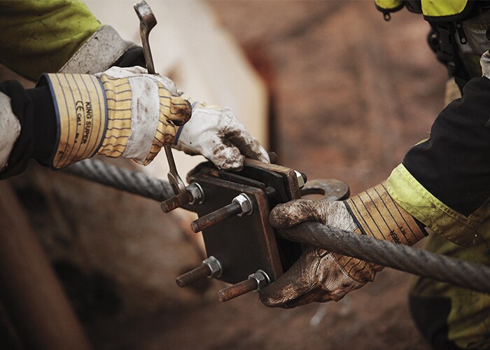 Two sets of hands working on a piece of machinery
