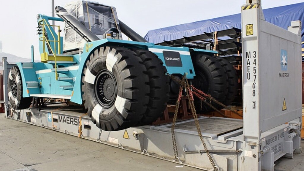 A large, heavy-duty piece of machinery, is secured on a flatbed container