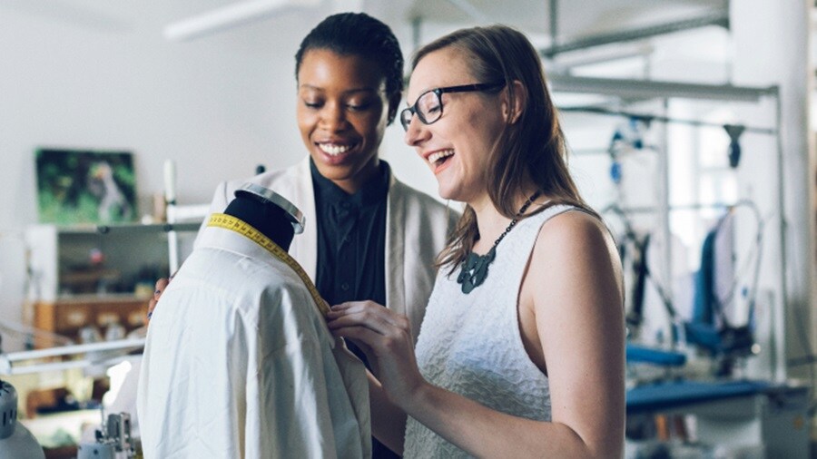 Two women, with smiles on their faces, are measuring.