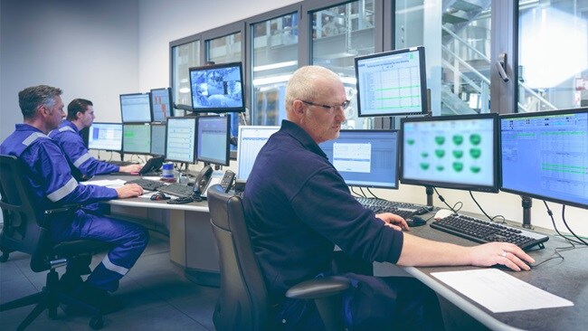 Three male working in an office in front of multiple screens