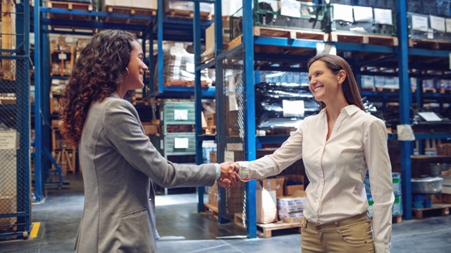 Two women shaking hands in warehouse