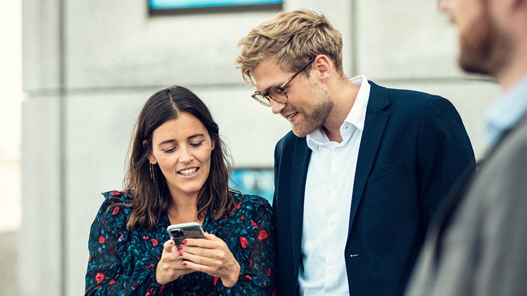 Two colleagues standing outside the office, reading Europe Market Update on a phone.