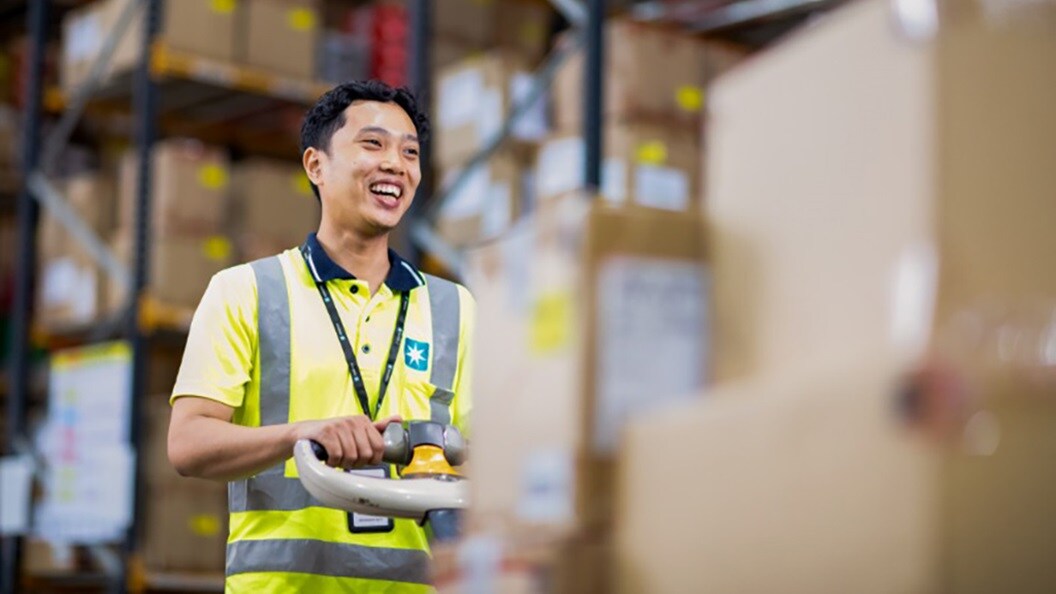 A warehouse worker surrounded by boxes in warehouse