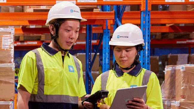 Two warehouse workers in safety helmets and high-visibility shirts.