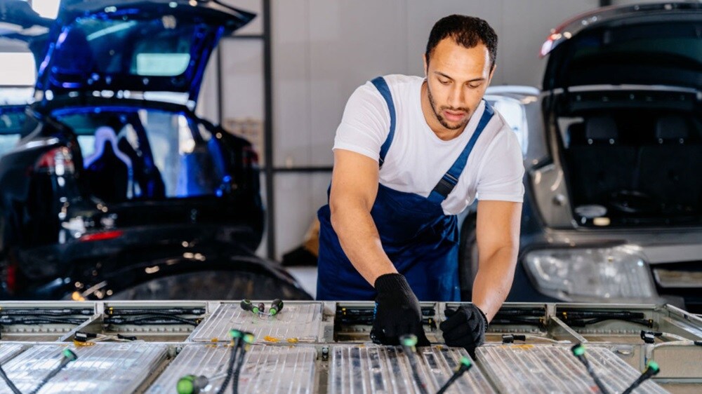 A man performing car maintenance in a garage, using tools and equipment to work on the vehicle.