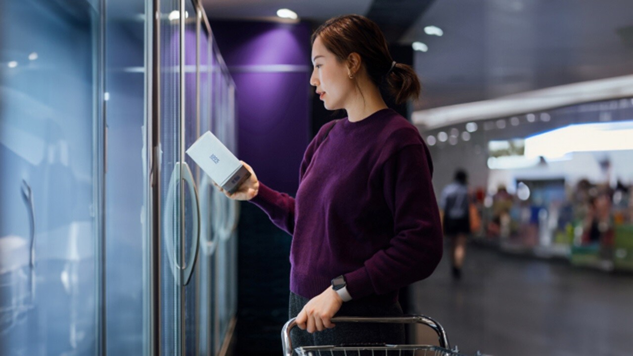 A lady in a shopping market, look at products inside a refrigerator