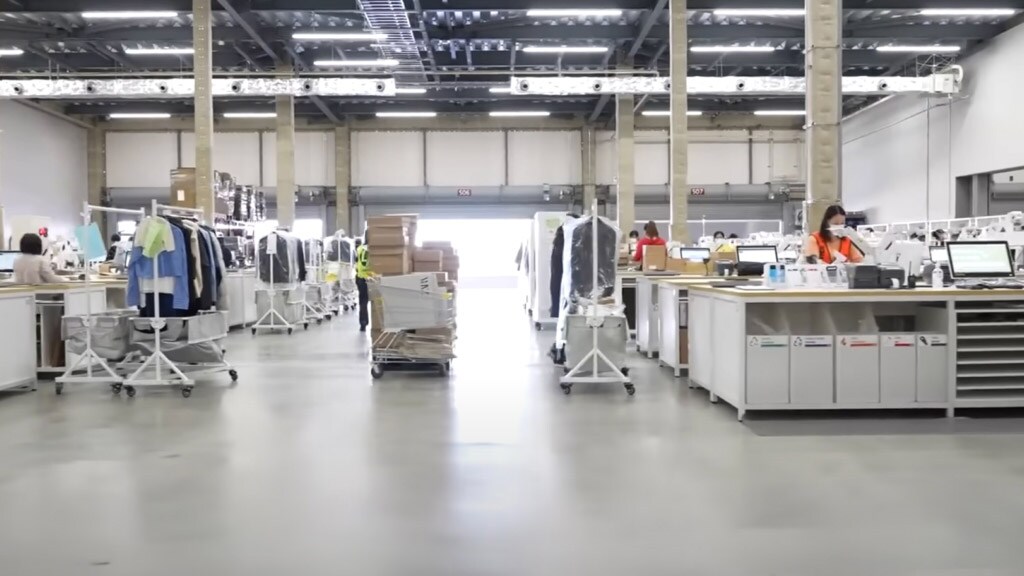 Modern logistics center with staff managing warehouse operations and clothing racks