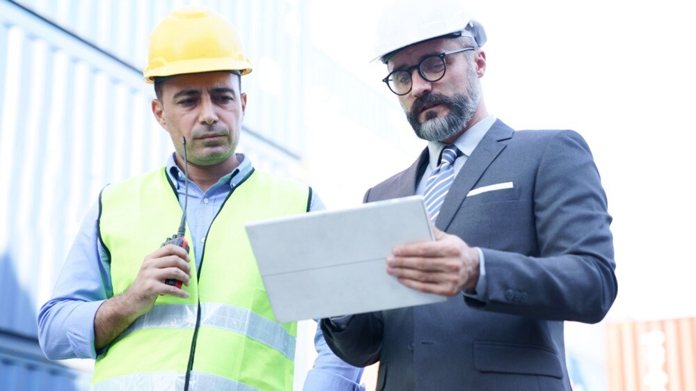 Dijital bir cihaz kullanarak sevkiyat ayrıntılarını koordine eden liman çalışanları