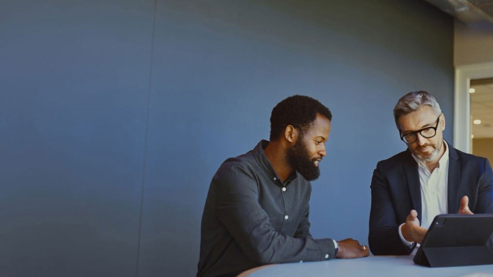 Deux hommes d’affaires discutent des éléments essentiels de l’ECTN tout en s’appuyant sur une tablette numérique.