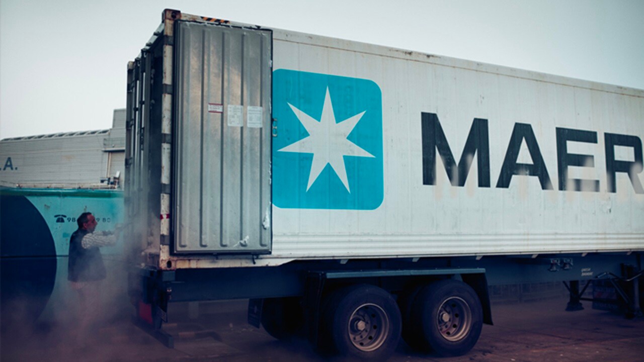 Um contêiner Maersk com portas abertas e um homem perto dele