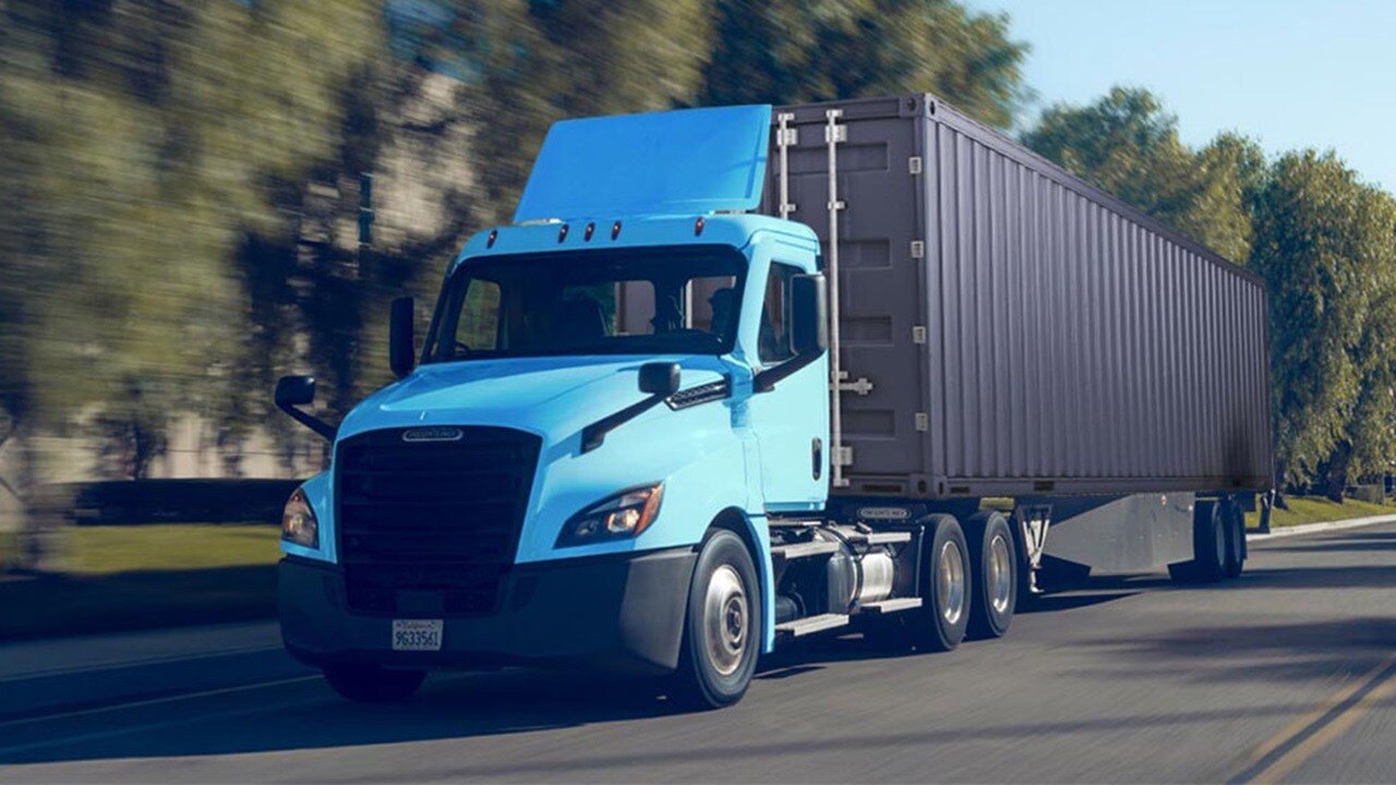 A blue semi truck driving along a highway.
