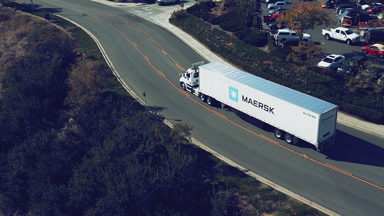 A Maersk shipping container truck on a highway
